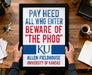 A framed sign with the text "PAY HEED ALL WHO ENTER BEWARE OF "THE PHOG" KU" from Allen Fieldhouse University of Kansas.