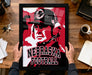 A framed poster of a football coach is being held up by a person's hands, with the text "NEBRASKA FOOTBALL" prominently displayed on the poster.