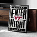 A framed poster with the text "ENTER NIGHT" and a Virginia Tech logo, placed on a carpeted floor next to a wooden chest.