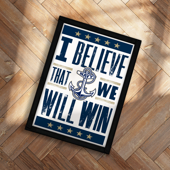 A framed poster with the text "I Believe That We Will Win" and an anchor symbol, placed on a wooden floor.