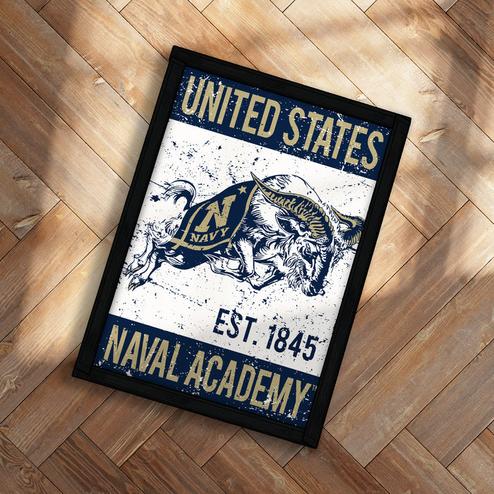 A framed poster with the text "UNITED STATES NAVAL ACADEMY EST. 1845" and an illustration of a bull wearing a naval hat.