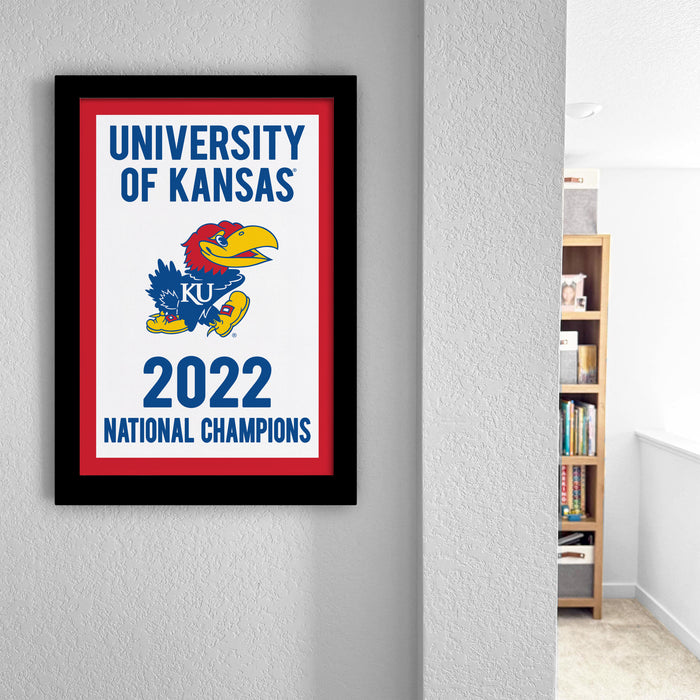 A framed poster on a wall celebrating the University of Kansas' national championship victory in the year 2023.