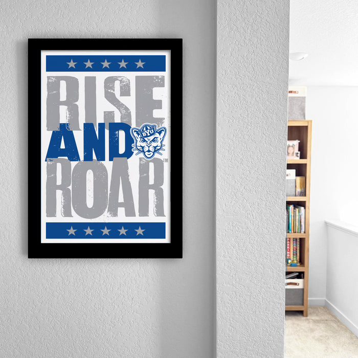 a framed poster with the text "RISE AND ROAR" and a cat graphic, hanging on a wall.