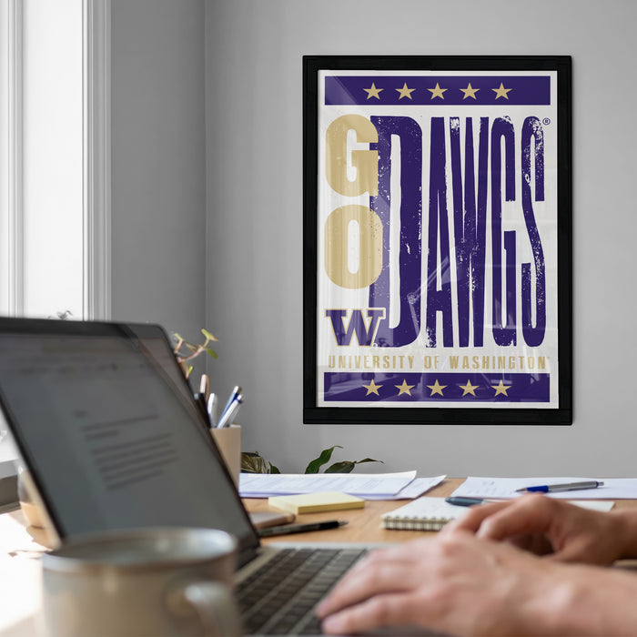 a framed poster of the University of Washington's "Go DAWG'S" team on the wall, with a laptop and desk in the foreground.