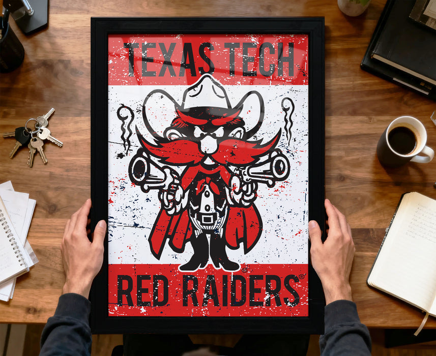 A framed poster featuring a cartoon character with a gun and the text "Texas Tech Red Raiders" is being held by a person's hands.