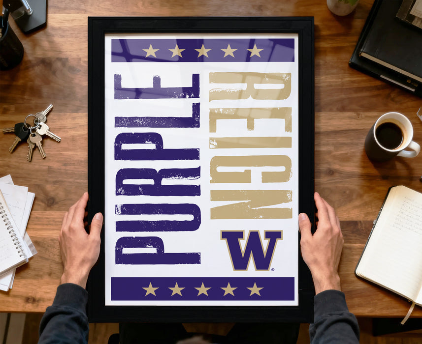 A framed poster with the text "Purple Reign" is being held by a person's hands, with a wooden desk and various office items in the background.