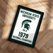 A framed poster with the text "Michigan State University" and "National Champions" on it, along with a graphic of a helmet and the year "1979".