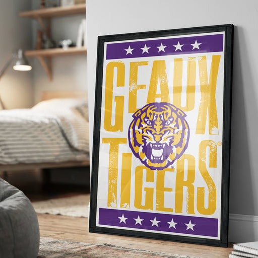 A framed poster with the text "GEAUX TIGERS" and a graphic of a tiger's head, displayed on a wall in a bedroom setting.