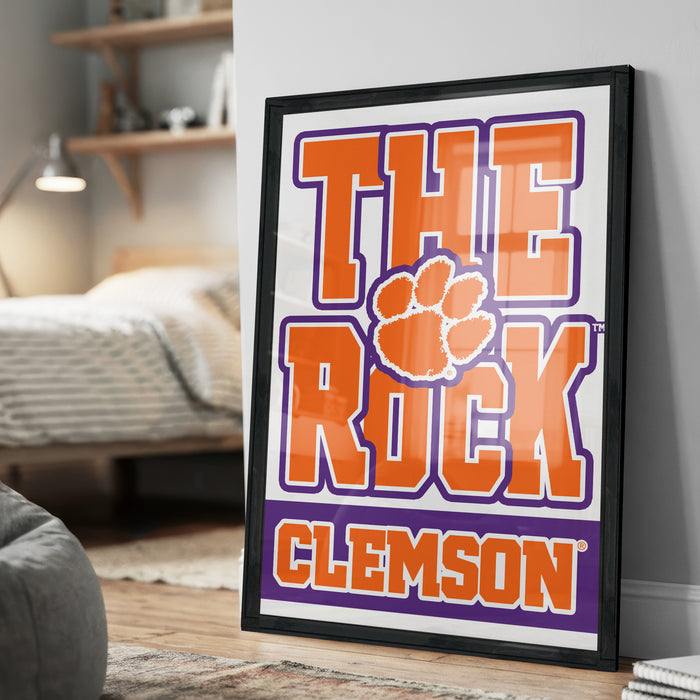 A framed poster with the text "THE ROCK CLAMS" and a paw print logo, displayed on a wall in a bedroom setting.