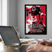 a framed poster of a football coach with the text "NEBRASKA FOOTBALL" on it, hanging on a wall above a desk with a laptop and other items on it.