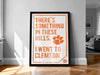 a framed poster with the text "There's something in these hills. I went to college" and an orange paw print symbol.