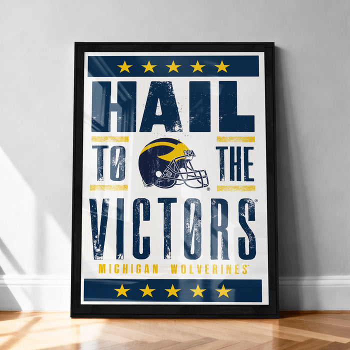A framed poster with the text "Hail to the Victors" and a football helmet graphic, promoting Michigan Wolverines.
