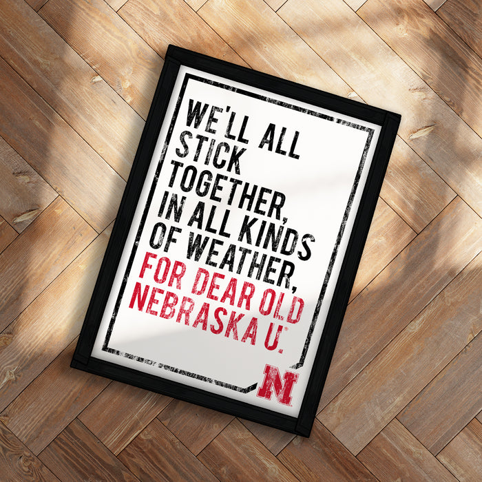 a framed quote with the text "WE'LL ALL STICK TOGETHER IN ALL KINDS OF WEATHER FOR DEAR OLD NEBRASKA U."
