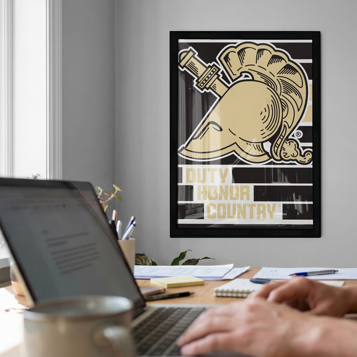 a person working on a laptop at a desk, with a framed poster of a military symbol hanging on the wall behind them.