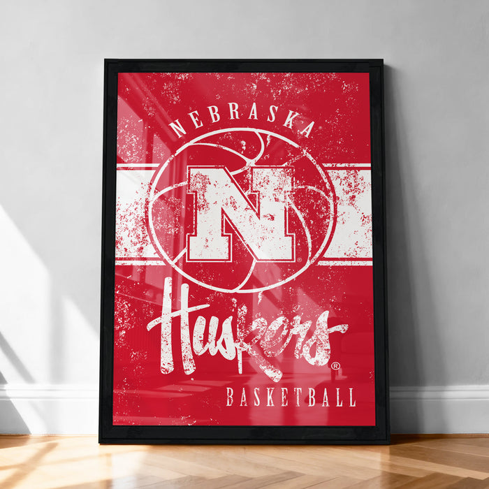 A framed poster of the Nebraska Huskies basketball team, featuring the team's logo and name on a red background.
