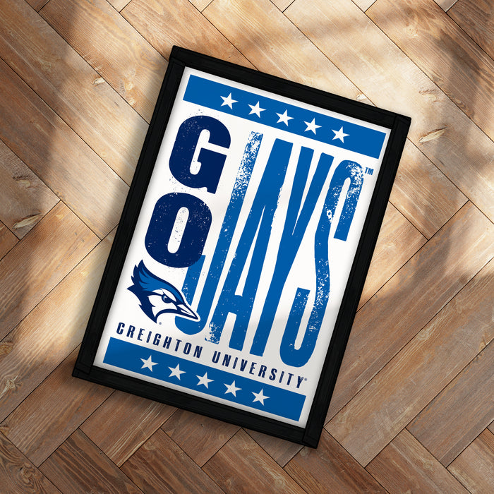 A framed poster with the text "GAYS" and "GREIGHTON UNIVERSITY" printed on it, placed on a wooden floor.