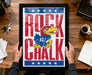 A framed poster featuring a cartoon bird character with the text "ROCK CHALK" prominently displayed.