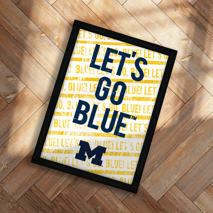 A framed poster with the text "LET'S GO BLUE" printed on it, placed on a wooden floor.
