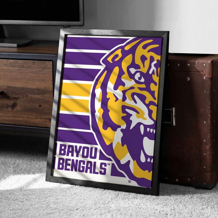 A framed poster of the LSU (Louisiana State University) logo is displayed on a carpeted floor next to a wooden chest.