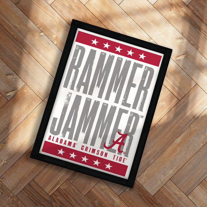 a framed poster with the text "RAMMER JAMMER" and "ALABAMA CRIMSON TIDE" printed on it, placed on a wooden floor.