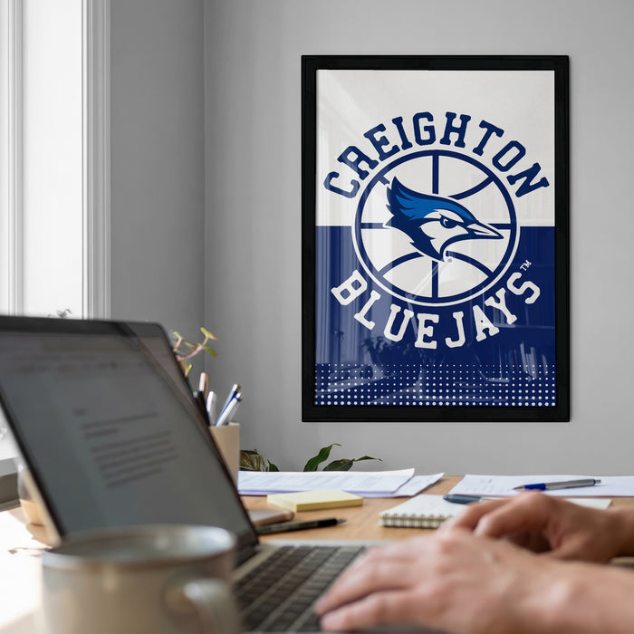A framed poster of the Toronto Blue Jays basketball team hangs on a wall, with a laptop and coffee mug on a desk in the foreground.