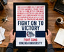 a person holding a framed poster with text and a bulldog logo, placed on a wooden desk.