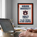 a framed poster of Auburn University from 1957, with a person's hands typing on a laptop in the foreground.