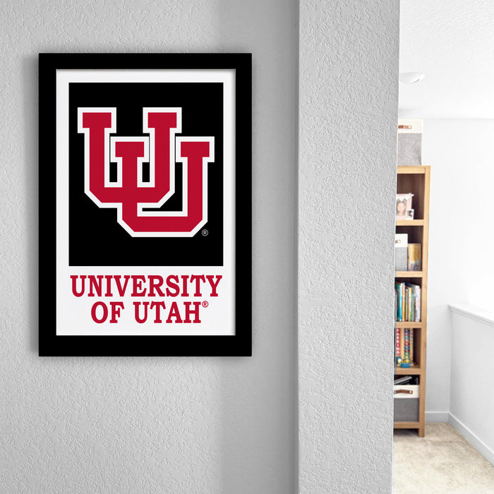 a framed poster of the University of Utah logo hanging on a wall.