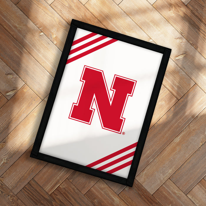 A framed poster with the letter "N" on it, placed on a wooden floor.