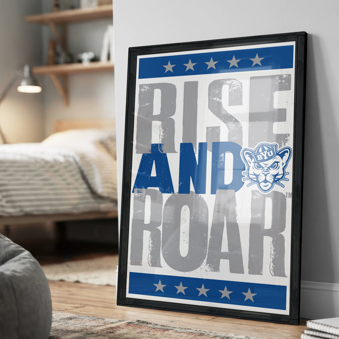 a framed poster with the text "RISE AND Roar" and a cat logo, displayed on a wall in a bedroom setting.