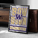 A framed poster with the text "BOW W down WASHINGTON" is displayed on a carpeted floor next to a wooden chest.
