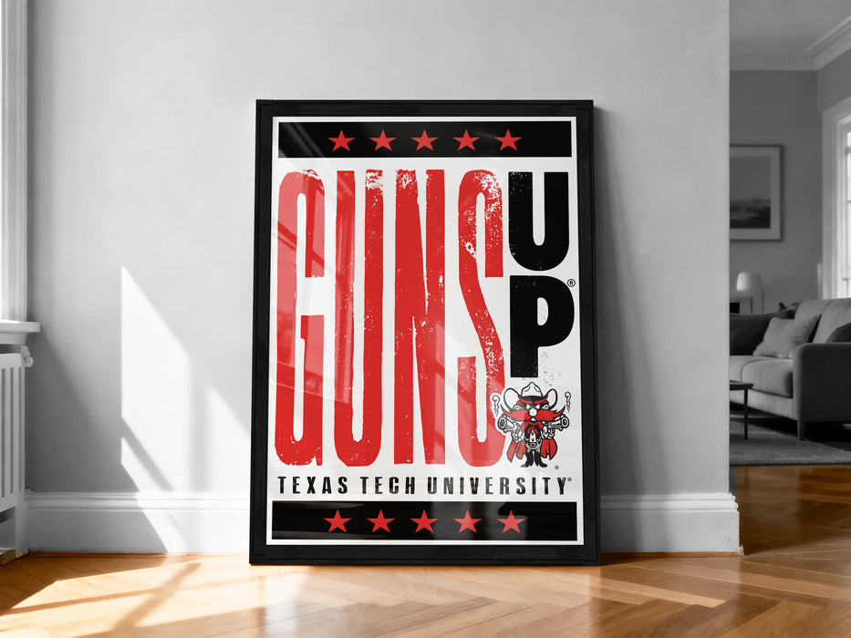 A framed poster with the text "GUNS UP" prominently displayed, along with a graphic of a gun and a star. The poster is placed on a wooden floor in a room with a couch and a window.