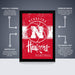 The image is a poster featuring the Nebraska Huskies basketball team. It is a red poster with white text and graphics, including arrows pointing to different parts of the poster. The poster is described as " Officially licensed" and "Premium printed", indicating that it is a high-quality, professionally printed poster. The poster is also described as "Shipped flat" and "The perfect gift", suggesting that it is a thoughtful and practical gift option.