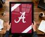 A person is holding a framed picture with the letter "A" on it, which appears to be a sports team logo.