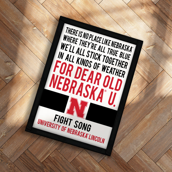 The image is a framed poster with text that reads "There is no place like Nebraska where they're all true blue, we'll all stick together in all kinds of weather for dear old Nebraska U. Fight Song University of Nebraska Lincoln".