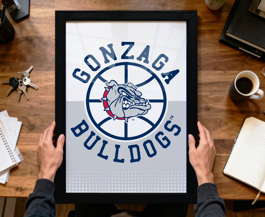 A person is holding up a framed poster with the Gonzaga Bulldogs logo on it, which features a bulldog in a basketball hoop design.