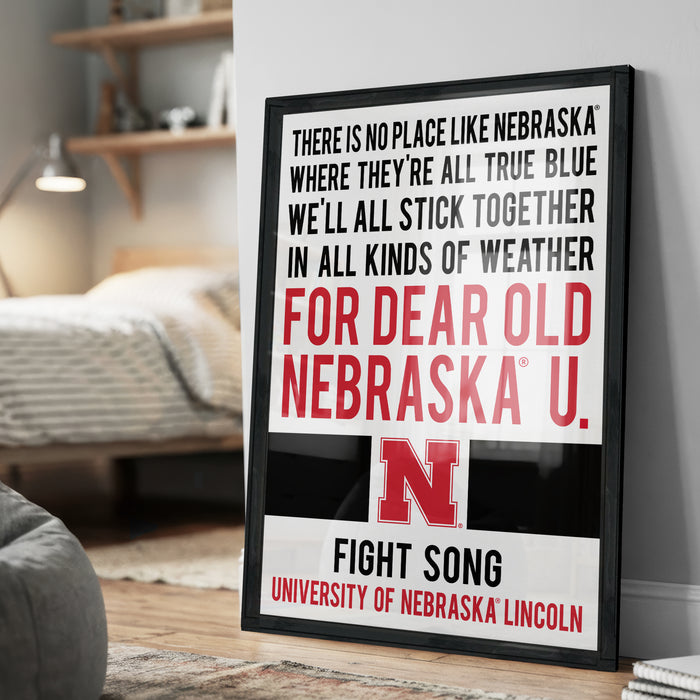 The image is a framed poster with text that reads "There is no place like Nebraska, where they're all true blue, where they're all stick together in all kinds of weather for dear old Nebraska U. FIGHT SONG UNIVERSITY OF NEBRASKA LINCOLN".