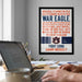 a framed poster with the text "WAR EAGLE, FEARLESS AND TRUE, FIGHT ON YOU ORANGE AND BLUE, GIVE 'EM HECKLING, GIVE 'EM HELL, STAND UP AND YELL, HELL, WIN FOR AUBURN, POWER OF DIXIELAND!" The poster is displayed on a wall above a desk with a laptop and other items.