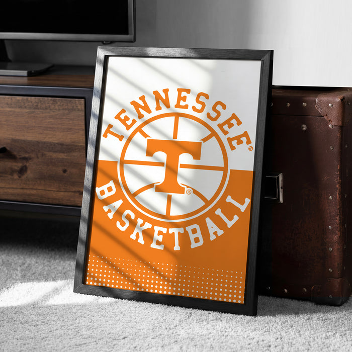 A framed poster of the Tennessee basketball team logo is displayed on a carpeted floor next to a wooden chest.