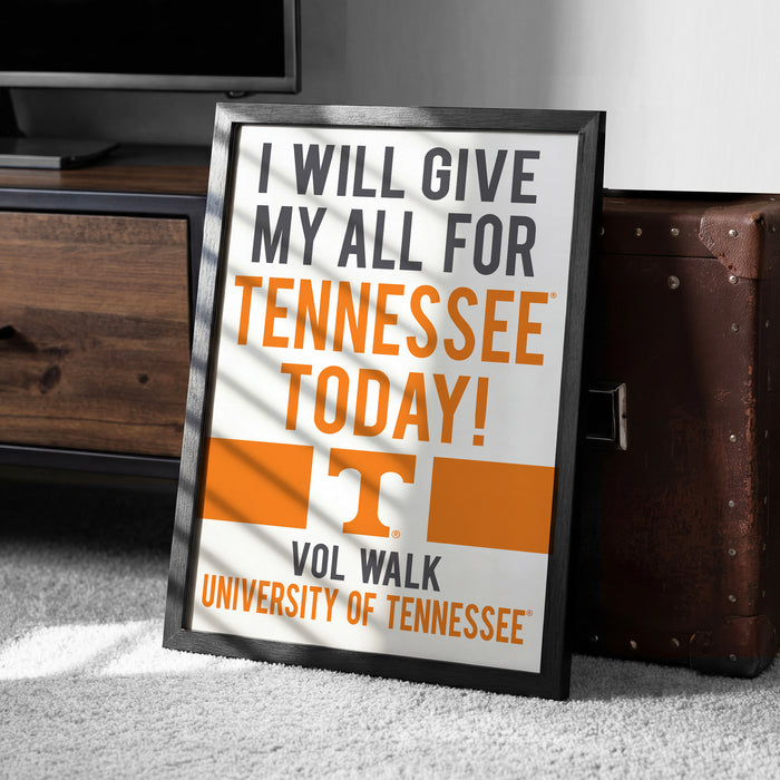 A framed poster with the text "I WILL GIVE MY ALL FOR TENNESSEE TODAY!" and the University of Tennessee logo, placed on a carpeted floor next to a wooden chest.