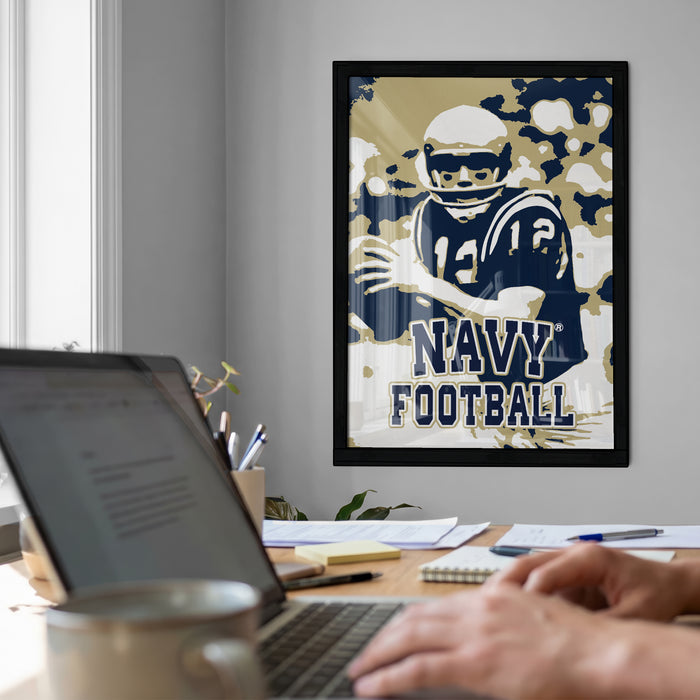 a framed poster of a football player on the wall, with a laptop and a coffee cup on a desk in the foreground.