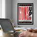 A framed poster with the word "GUNS" prominently displayed, along with a Texas Tech University logo, hangs on a wall in a room with a desk and laptop.