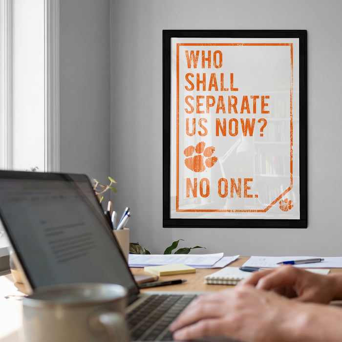 a framed motivational quote on the wall, with a laptop and a coffee mug on a desk in the foreground.
