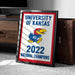 A framed poster with the text "UNIVERSITY OF KANSAS" and "2022 NATIONAL CHAMPIONS" on it, along with a graphic of a bird, is placed on the floor next to a wooden chest.