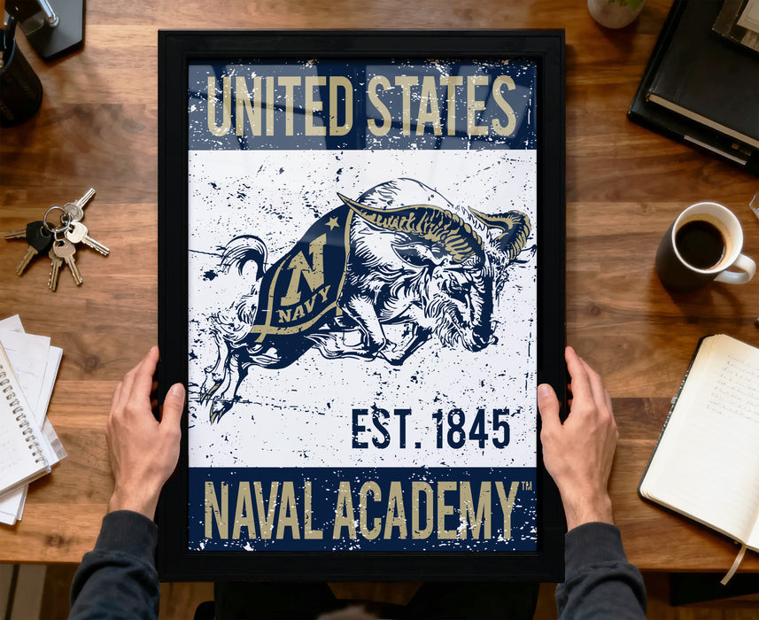 A framed poster with the text "UNITED STATES NAVAL ACADEMY EST. 1845" and an illustration of a naval officer on a horse.