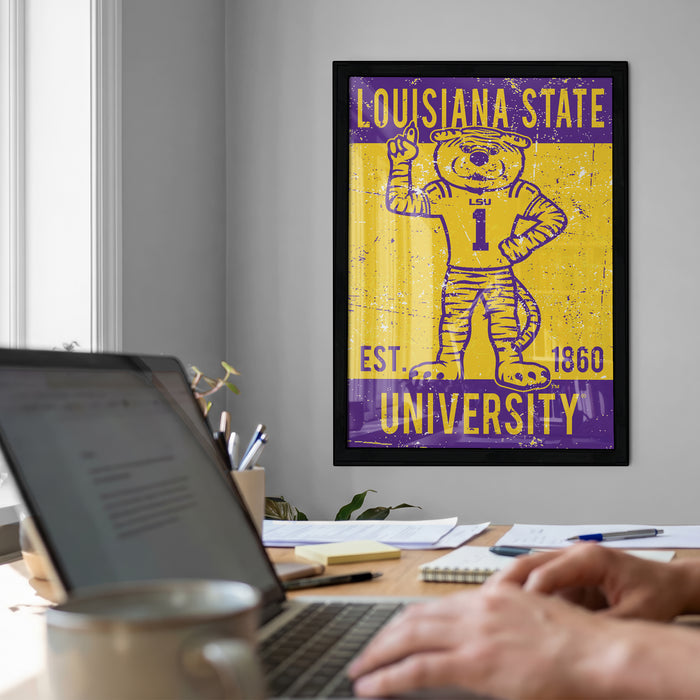 a framed poster of a tiger mascot from Louisiana State University, with a laptop and a coffee mug on a desk in the foreground.