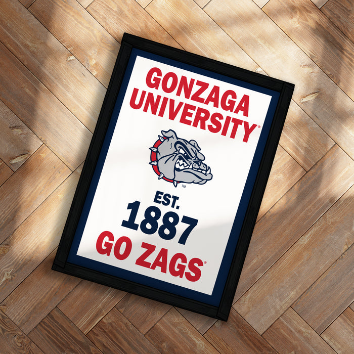 A framed poster with the text "GONZAGA UNIVERSITY EST. 1887 GO ZAGS" and a bulldog logo, placed on a wooden floor.