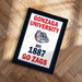 A framed poster with the text "GONZAGA UNIVERSITY EST. 1887 GO ZAGS" and a bulldog logo, placed on a wooden floor.
