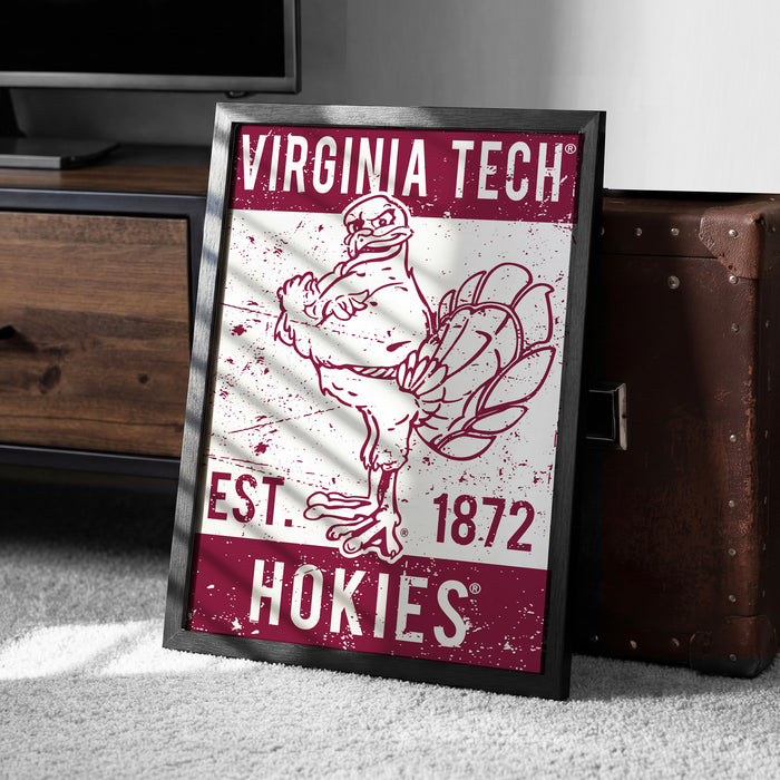 A framed poster featuring a turkey and the text "VIRGINIA TECH EST. 1872 HOKIES" is displayed on a carpeted floor next to a wooden chest.