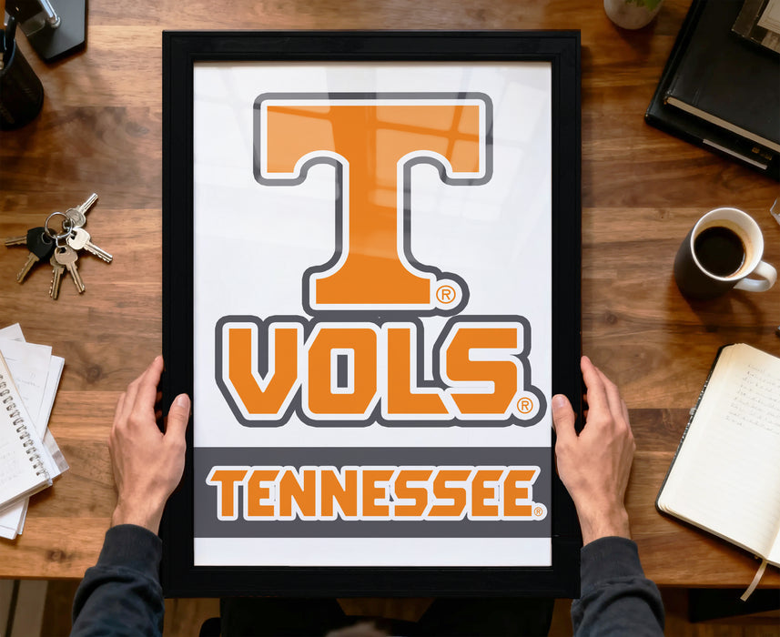 A person is holding a framed picture of the Tennessee State University (TSU) logo, which is an orange letter "T" with a registered trademark symbol.